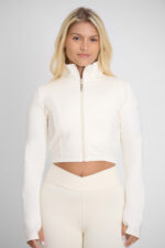 Jaqueta Kim Macadâmia: jaqueta cropped cor creme combinando com leggings.