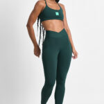 LEGGING KALI FLORESTA: Mulher vestindo conjunto esportivo verde, incluindo top e legging.
