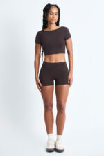 Mulher vestindo SHORT EMA CACAU marrom, top cropped e shorts combinando.