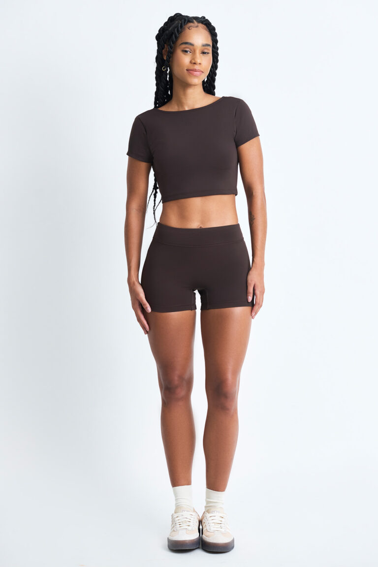 Mulher vestindo SHORT EMA CACAU marrom, top cropped e shorts combinando.