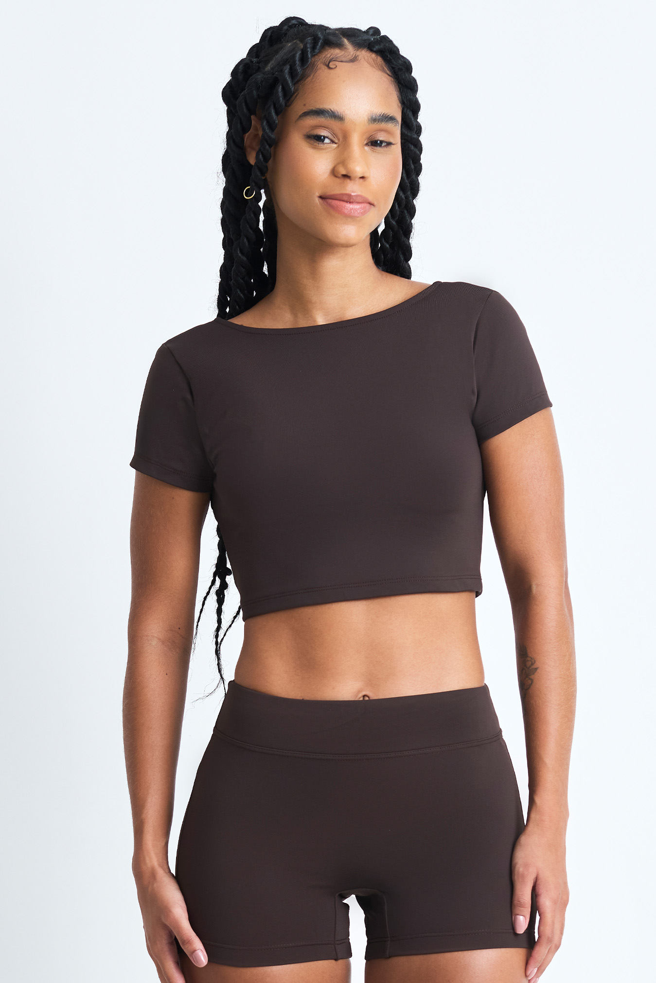 short ema cacau frente Short Ema Cacau: Conjunto marrom de top cropped e shorts, ideal para exercícios ou uso casual.