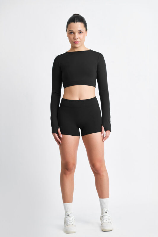 Mulher vestindo SHORT EMA SOFT NANQUIM preto, top cropped de manga comprida, em fundo branco.