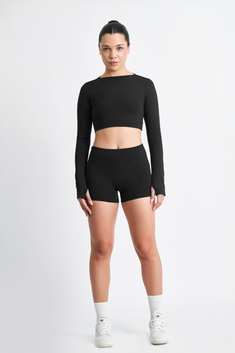 Mulher vestindo SHORT EMA SOFT NANQUIM preto, top cropped de manga comprida, em fundo branco.