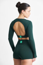Mulher vestindo SHORT YANI FLORESTA verde, top cropped de manga longa com recorte nas costas e shorts combinando.