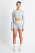 Short Yani Lunar: shorts esportivos cinza com cós em V e blusa cropped de manga comprida combinando.