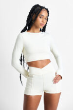 Mulher vestindo SHORT YANI MACADÂMIA cor creme, top cropped e shorts combinando.