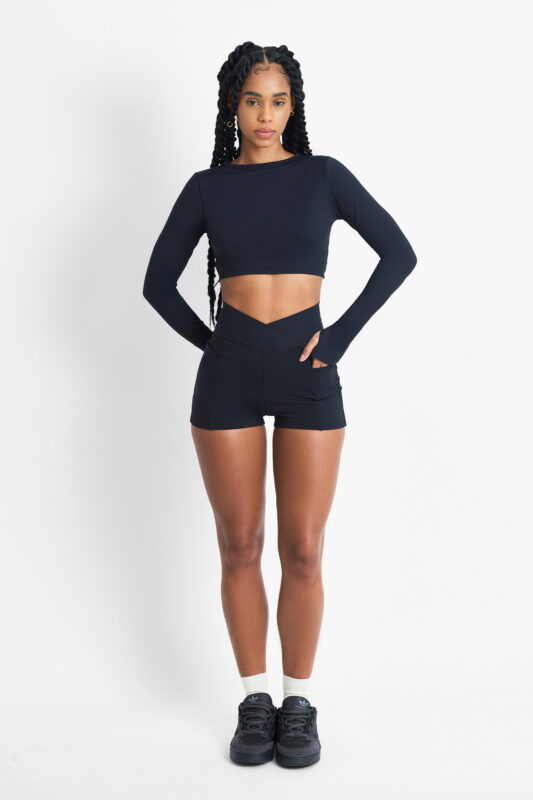 Mulher usando SHORT YANI SOFT NANQUIM preto, top cropped e tênis pretos.