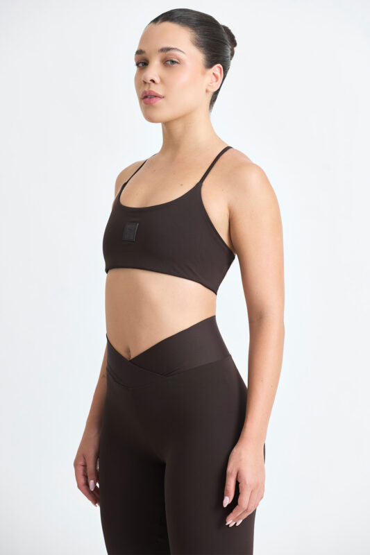 Mulher vestindo TOP AXY CACAU e legging marrom para treino ou yoga.