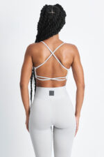 TOP AXY LUNAR: Top esportivo feminino cinza claro com design de tiras cruzadas nas costas.