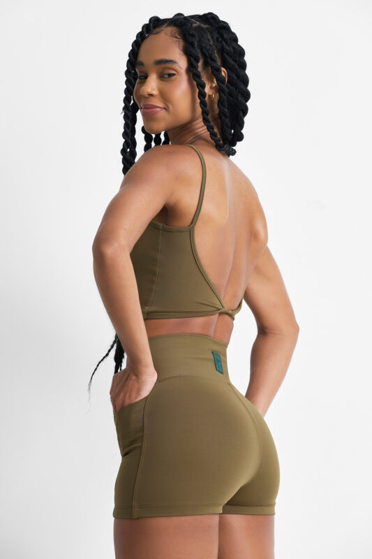 TOP NOMA SOFT SAVANA: Top esportivo feminino verde oliva com design moderno e costas abertas.