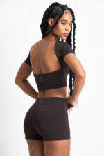 TOP AMÉLIA CACAU: Top cropped marrom com design moderno e costas abertas, ideal para treinos e looks casuais.
