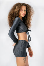Mulher com cabelo afro e conjunto curto cinza texturizado. Estilo moderno e casual.